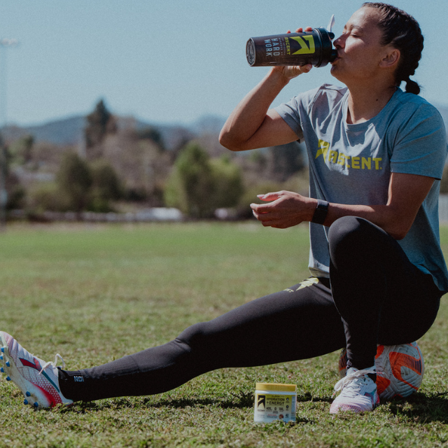 split_row_banner_1 ali riley ascent protein powder athlete sitting atop a soccer ball drinking clean hydration plus energy  powder in raspberry lemonade flavor